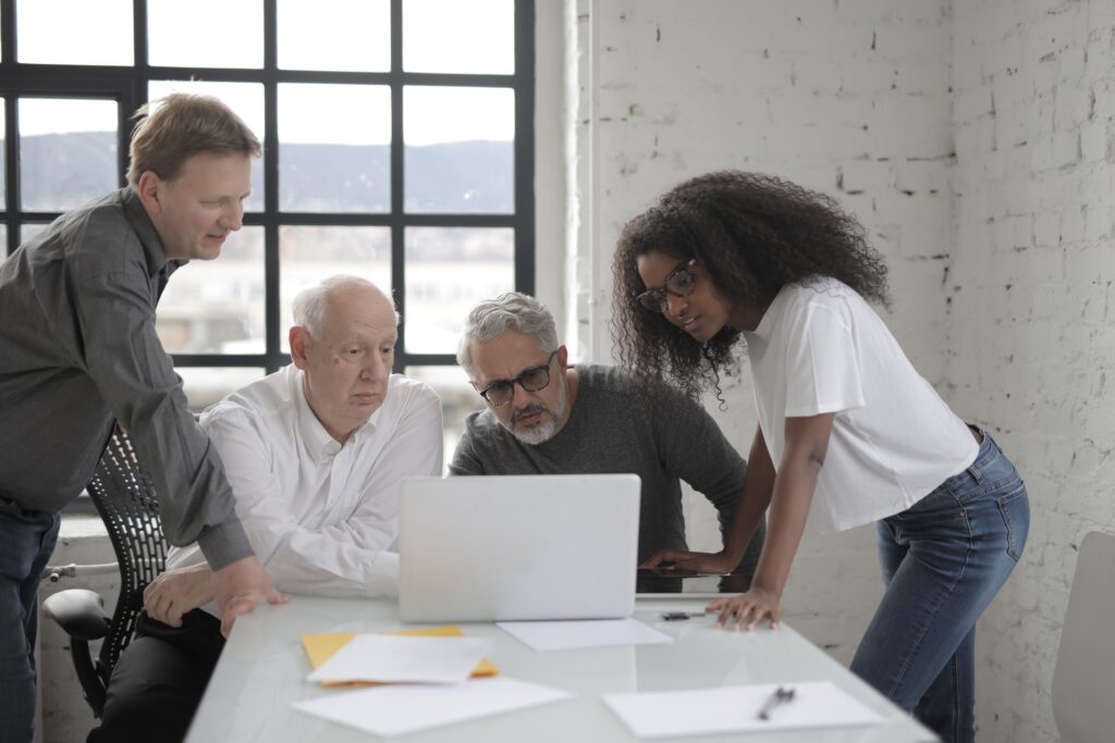 Business team collaborating in a modern office space, reviewing information on a laptop.
